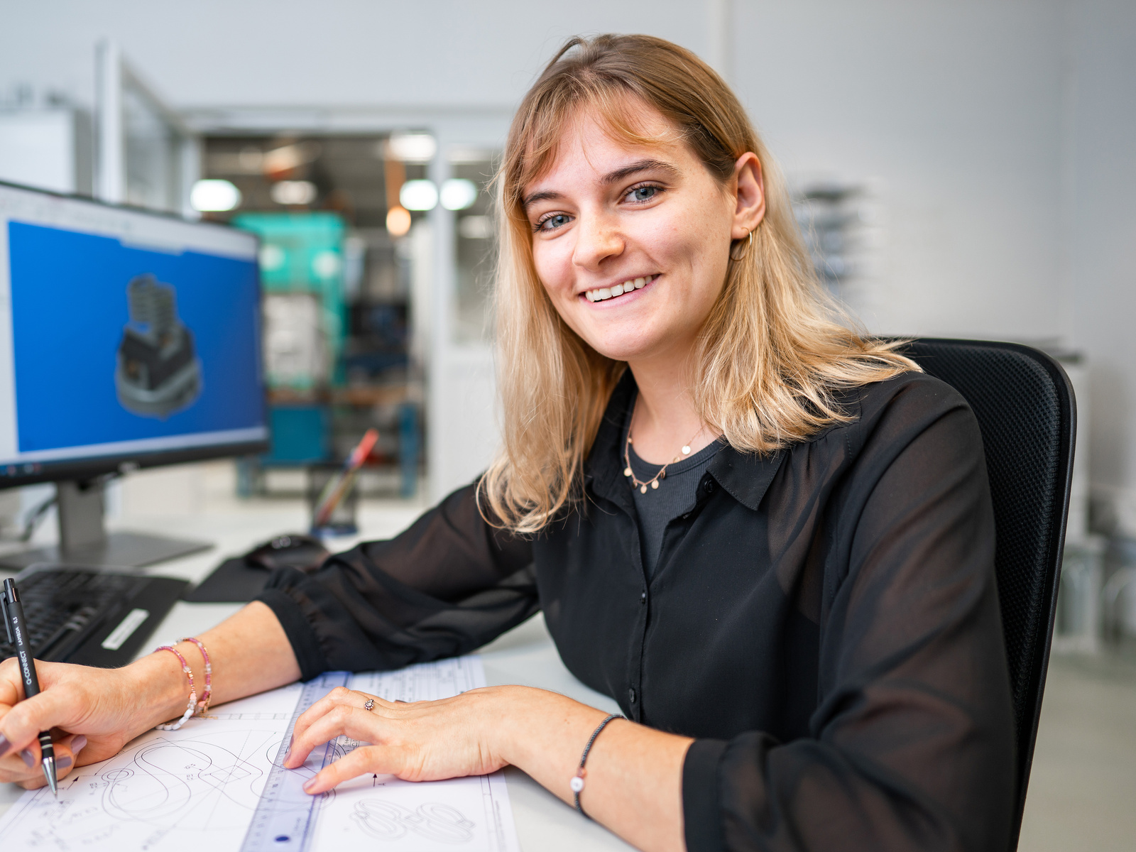 Frau am Arbeitsplatz lächelt in die Kamera | © Personal Sigma